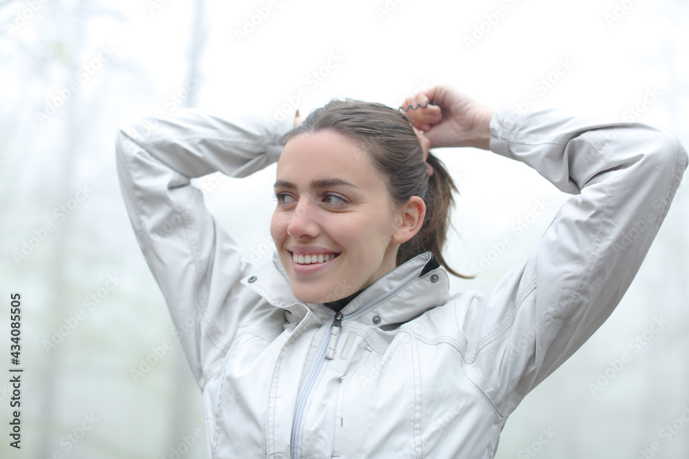 Happy hiker woman making a ponytail in a forest Happy hiker woman making a ponytail in a forest