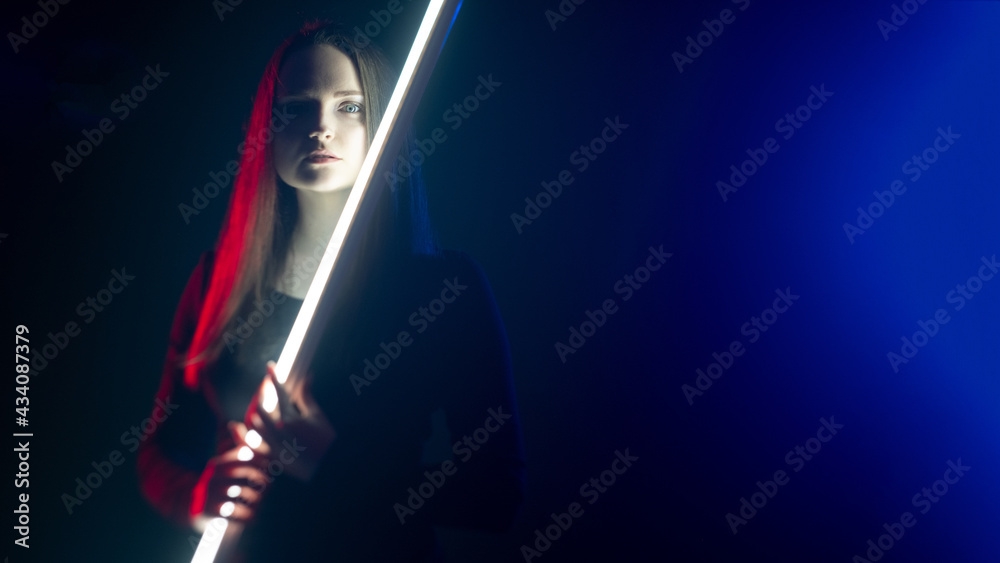 Cyberpunk fashion. Futuristic beauty. Fantasy power. Art portrait of mysterious cyborg woman with LED laser in red blue neon light on defocused dark night copy space background.