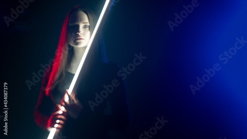 Cyberpunk fashion. Futuristic beauty. Fantasy power. Art portrait of mysterious cyborg woman with LED laser in red blue neon light on defocused dark night copy space background.