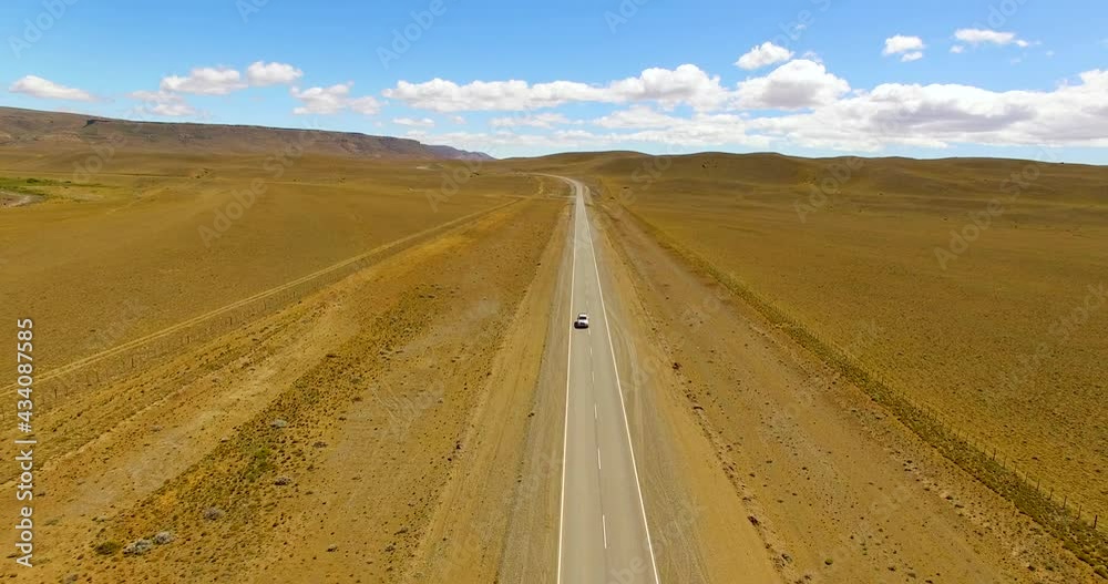 Aerial view overlooking a car on a desert road, in Argentina - reverse, drone shot Aerial view overlooking a car on a desert road, in Argentina - reverse, drone shot