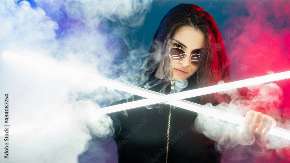 Cyberpunk girl. Futuristic portrait. Vaporwave party. Confident glamour woman in sunglasses in pink blue neon light white smoke cloud isolated on dark.