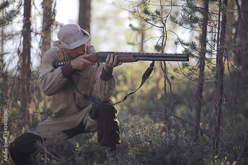 man goes hunting forest summer / landscape in the forest, huntsman with a hunting rifle hunts