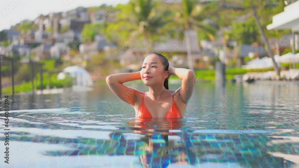 Asian model girl emerging from pool and strokes her wet hair. Slow-motion Asian model girl emerging from pool and strokes her wet hair. Slow-motion
