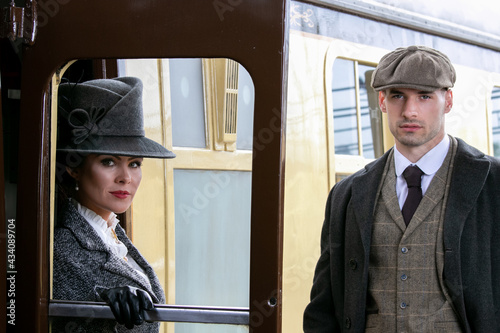 Beautiful woman dressed in vintage 1920s costume arriving by train and greeted by her bodyguard photo