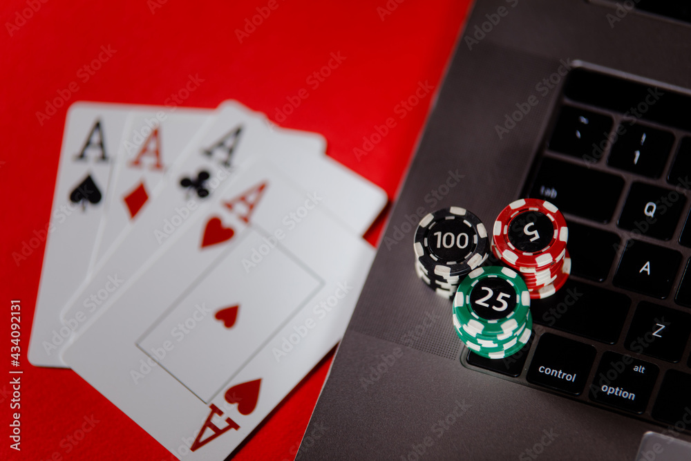 Obraz premium Poker cards, stacks of poker chips and laptop on a red background close-up. Poker online concept