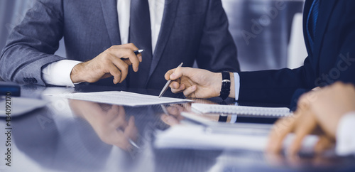 Unknown business people working together at meeting in modern office, close-up. Businessman and woman with colleagues or lawyers discussing contract at negotiation