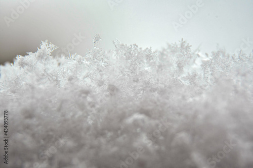 Macro photography of snowflakes. Closeup of fresh snow in winter. Geometric pattern. Christmas mood. Selective focus on the flakes, blurred background.