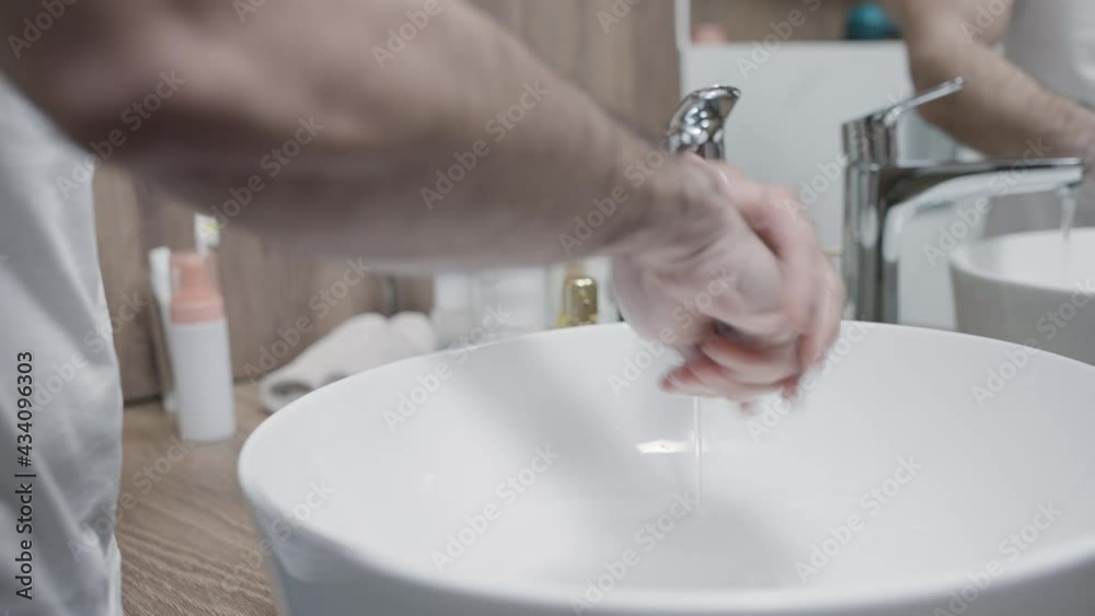 Young man washing hands in bathroom, personal hygiene during covid-19 pandemic Young man washing hands in bathroom, personal hygiene during covid-19 pandemic