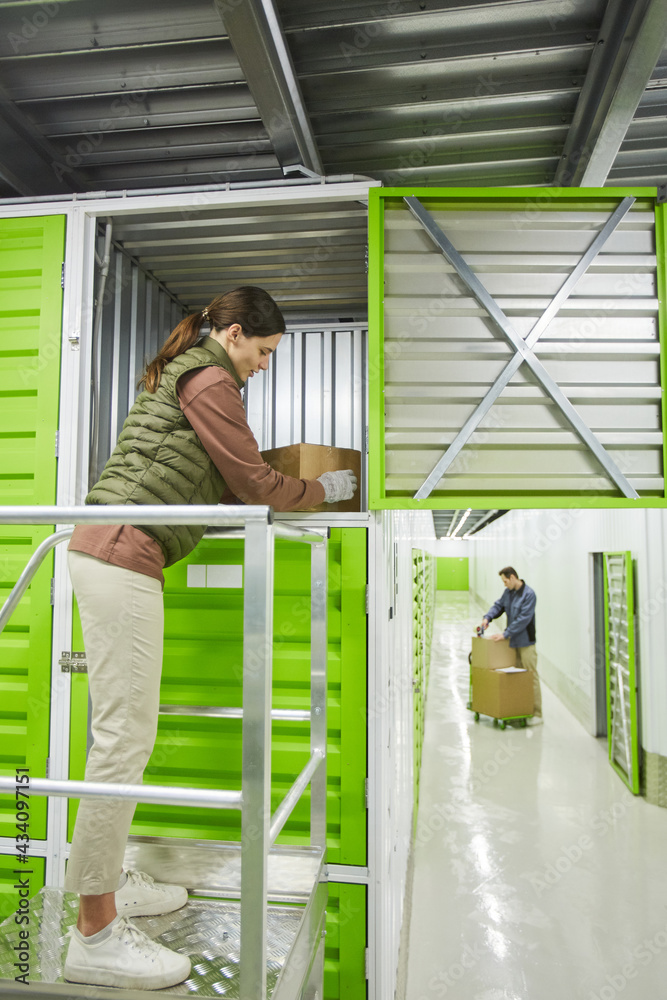 Young woman working in warehouse she packing parcels in storage box