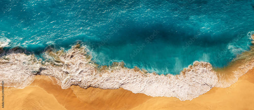 Aerial view of blue ocean waves in Kelingking beach, Nusa Penida island in Indonesia. Beautiful sandy beach with blue sea. Lonely sandy beach with beautiful waves. Panorama Beach. Copy space
