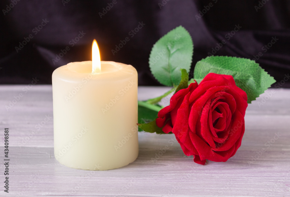 The concept of remembrance, funerals, and condolences. Candle and red rose on black background, free space for text The concept of remembrance, funerals, and condolences. Candle and red rose on black background, free space for text