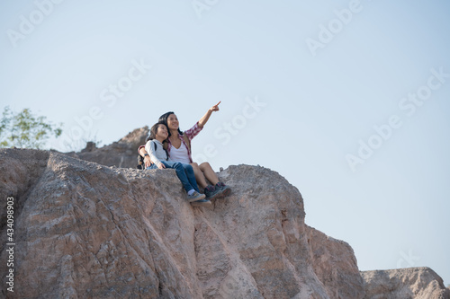 family travel- hikers with backpack looking at mountains view  mother with child at the day time  little girl with mother trekking on red trail  Concept of friendly family.