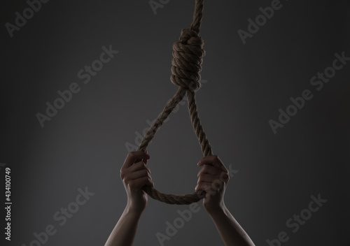 Woman holding rope noose on grey background, closeup