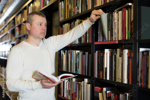 male absorbedly looking for interesting books on rack in bookstore