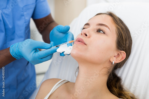 Young woman getting procedure of injection contouring and lip augmentation for facial correction in cosmetology clinic