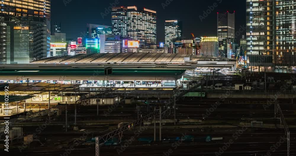 Time-lapse of traveling train at station platform, Japanese people waiting and boarding train, and office building cityscape in Tokyo, Japan. Asian city life or Asia transportation concept. Panning