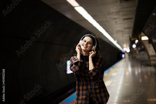 Young smiling woman outdoors. A young woman listening to music while waiting for the train.