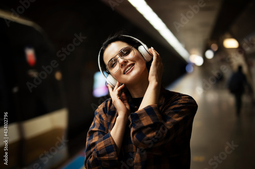 Young smiling woman outdoors. A young woman listening to music while waiting for the train.