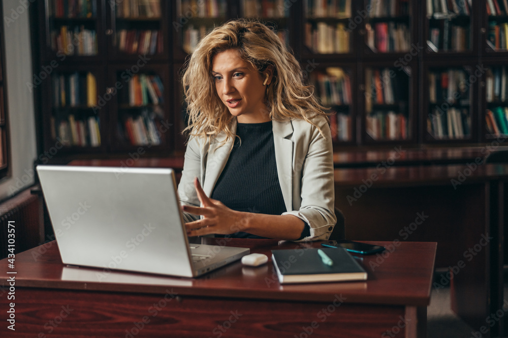 Businesswoman using a laptop for an online meeting while working in her office Businesswoman using a laptop for an online meeting while working in her office