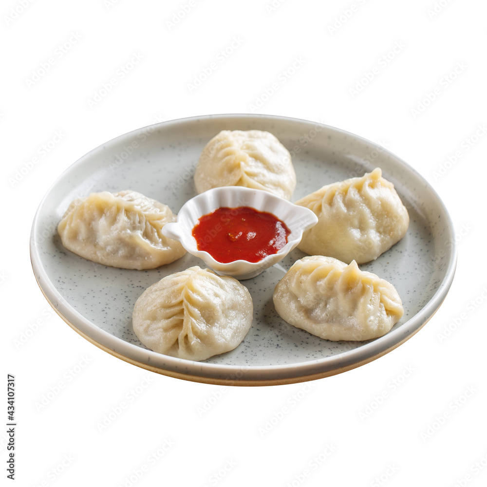 Isolated plate of manti dumplings with red sauce on white