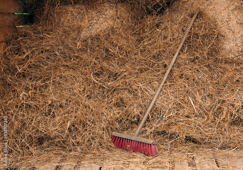 Fotografija Large wooden broom leaning on a pile of hay