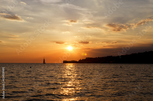 Picturesque seaside resort town in Slovenian coast against orange sunset sky in summer. Scenic view to Adriatic sea in the evening. Travel concept. 