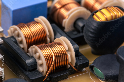 Close up of inductor copper coil on circuit board, copper wire winding soldered on printed, toroidal inductor, selective focus. photo