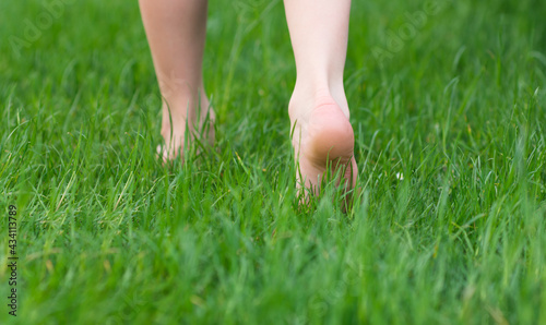 Kid foot walking in green grass on garden. Barefoot concept and healthy feet. 