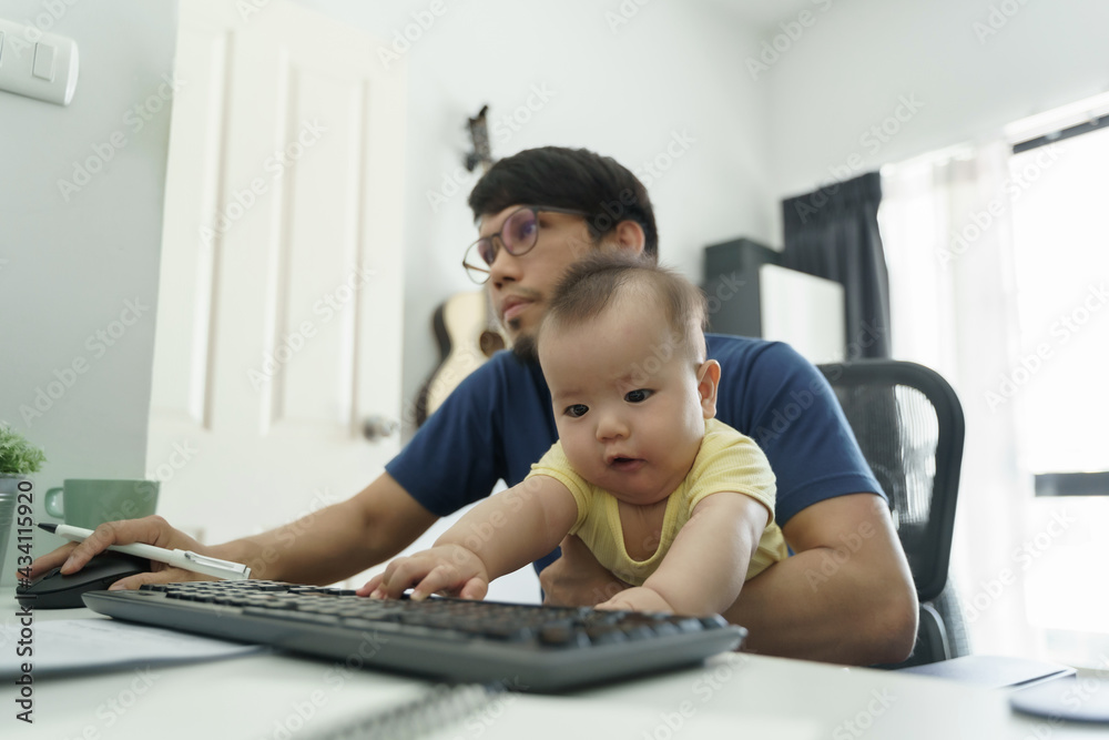 Young Asian freelance Designer man sitting doing a job on computer while taking care of his little baby boy son Young Asian freelance Designer man sitting doing a job on computer while taking care of his little baby boy son