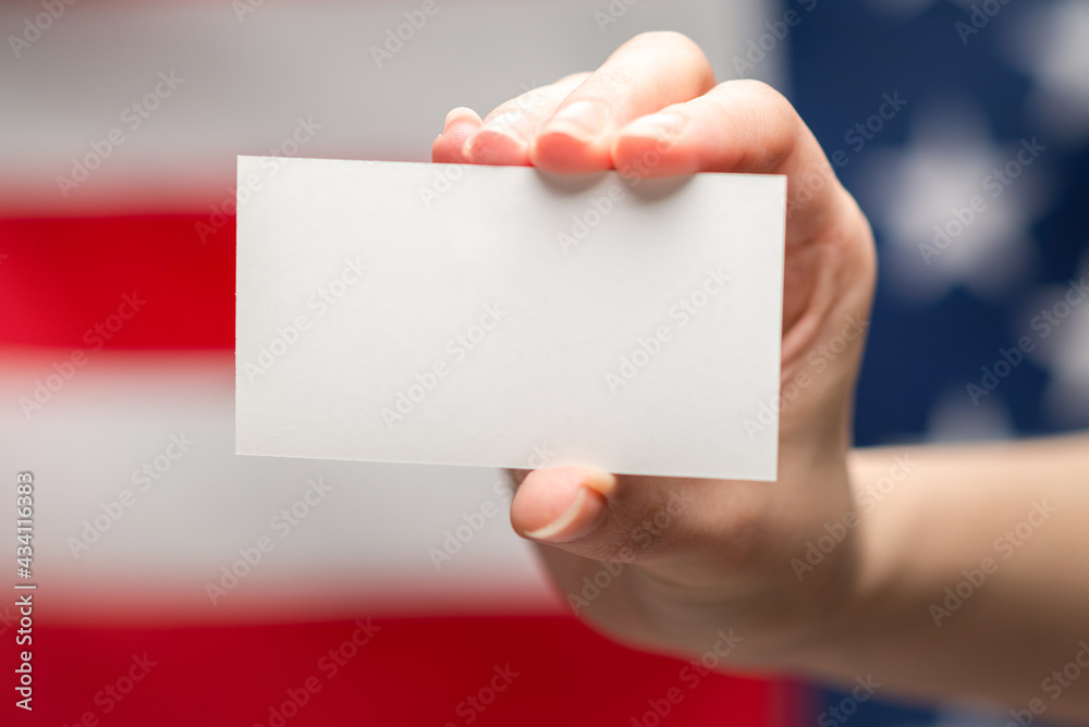 Empty card in woman hand. Copy space. American flag background. Empty card in woman hand. Copy space. American flag background.