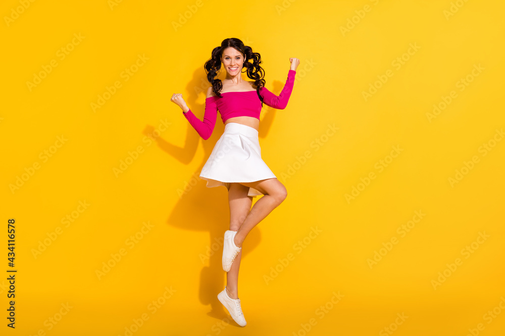 Full length body size view of pretty cheerful wavy-haired girl jumping having fun isolated over bright yellow color background