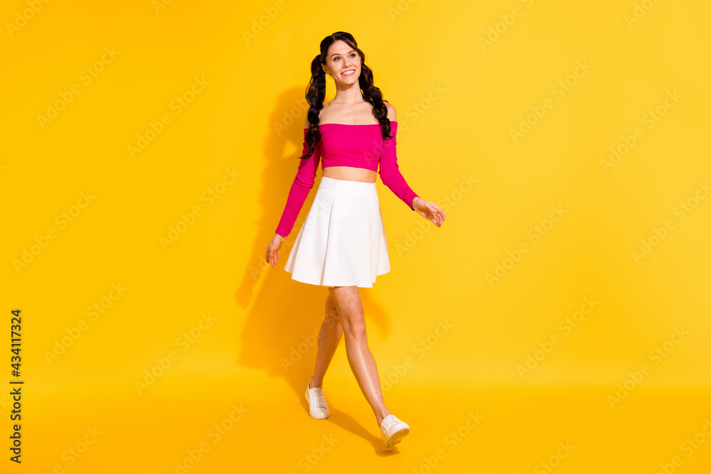 Full length body size view of charming cheerful slender wavy-haired girl going isolated over bright yellow color background Full length body size view of charming cheerful slender wavy-haired girl going isolated over bright yellow color background