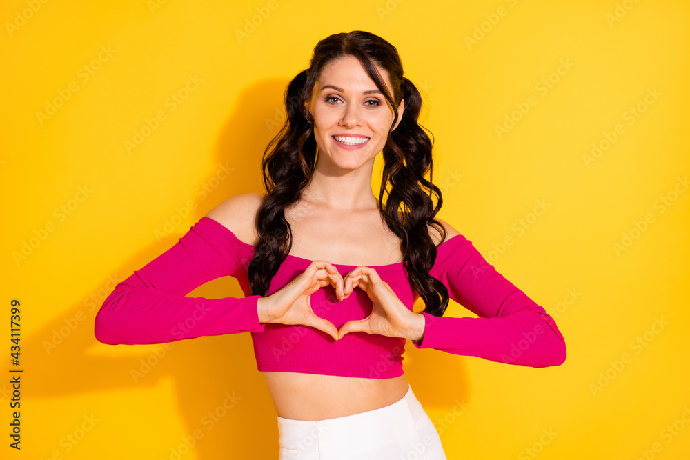 Obraz premium Photo of funny charming young woman wear pink top showing fingers heart isolated yellow color background