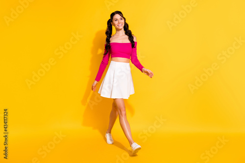 Full length body size view of charming cheerful slender wavy-haired girl going isolated over bright yellow color background