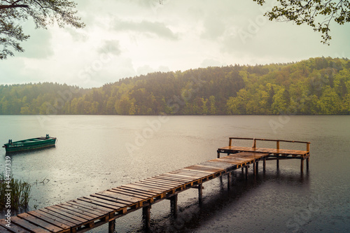 Drewniany pomost nad jeziorem w Łapinie w deszczowy dzień.