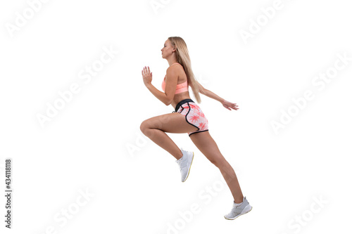 A sporty young woman in a pink top, shorts and sneakers runs forward on a white background