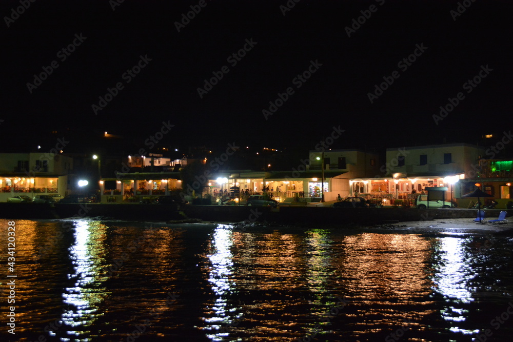 Cafe restaurant neighborhood in Syros island Greece at night next to colorful ocean