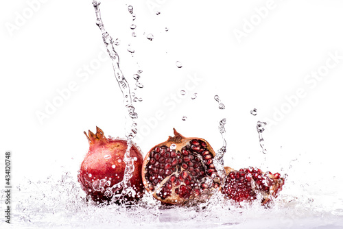Splash of fresh water on whole pomegranate fruits and succulent grains photo