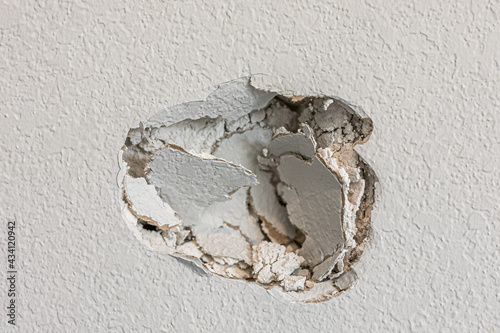 A hole in the wall of a hallways caused by a fist punching through the wall photo