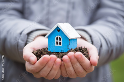 Wooden house model on plot of land in hands close up. Real estate business. Cottage for sale. Selling and buying home.