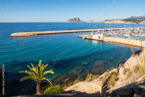 Maritime landscape with a breakwater with a small red lighthouse  in Moraira  Alicante  Spain 