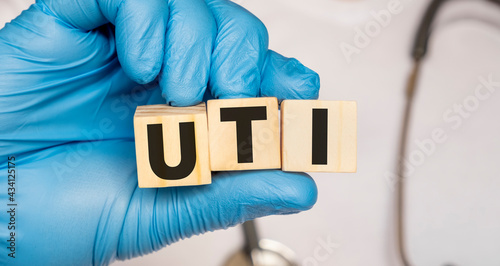 Fotografi UTI Urinary tract infection - word from wooden blocks with letters holding by a doctor's hands in medical protective gloves