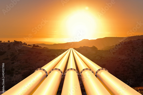 Fotografie Gas or oil pipeline pipes in mountainous terrain against the backdrop of sunset