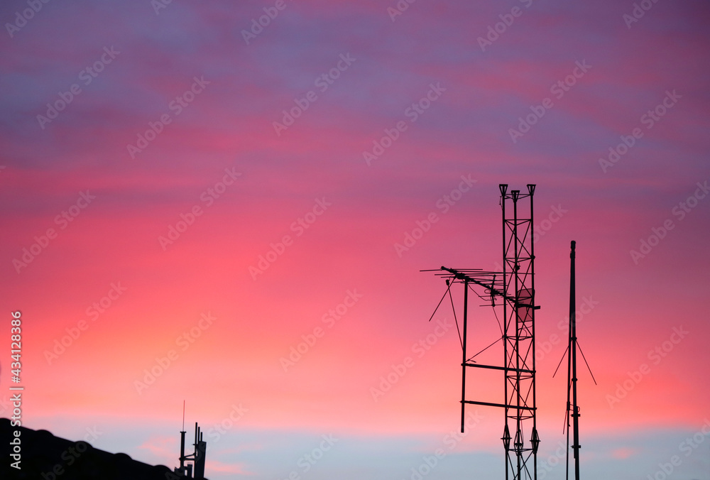 Selective focus at digital tv transmission tower on the roof with twilight background