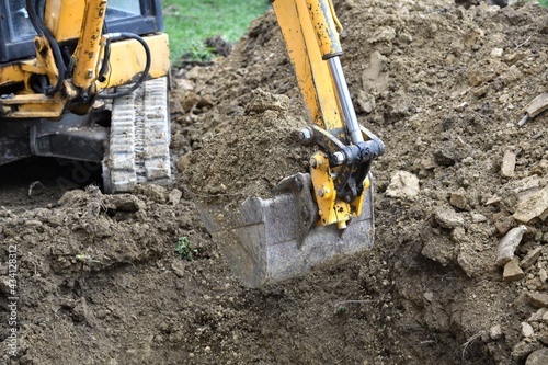 Obraz na płótnie A road excavator dredges the ground foundations near the house w salonie