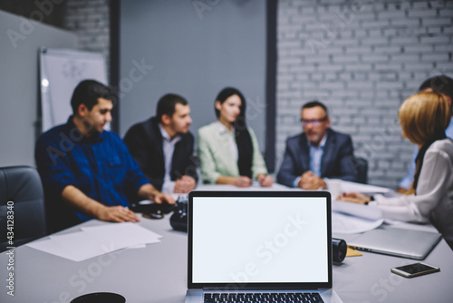 Team of blurred business entrepreneurs communicate at desktop with computer technology with mock up screen for web advertising  experts working at table with modern laptop device with blank screen