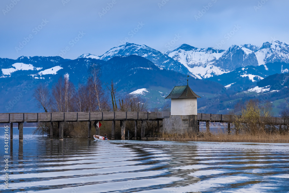View of the historic Husli chapel (Way of st. James) on the wooden pedestrian bridge crossing the Upper Zurich Lake (Obersee) near Rapperswil, St. Gallen, Switzerland