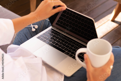 a woman hands holding a computer and a cup of coffee 