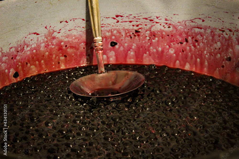 Chokeberry berries are cooked for jam. Cooking chokeberry jam. Chokeberry berries. Aronia. In a pot with a ladle.