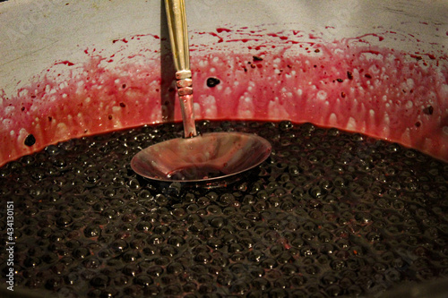 Chokeberry berries are cooked for jam. Cooking chokeberry jam. Chokeberry berries. Aronia. In a pot with a ladle.